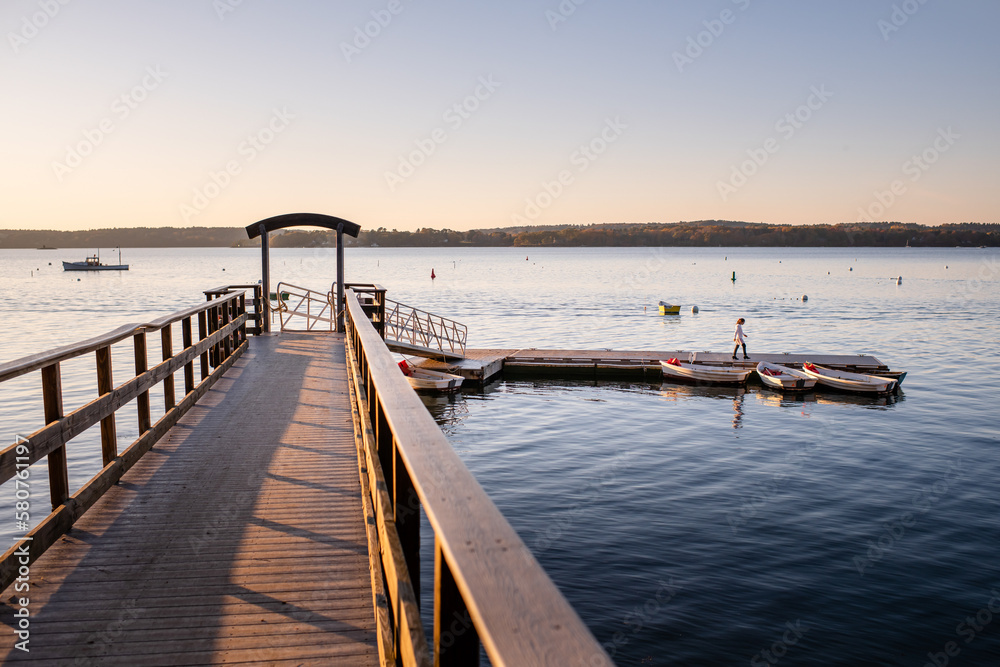 Girl walking on dock at sunset