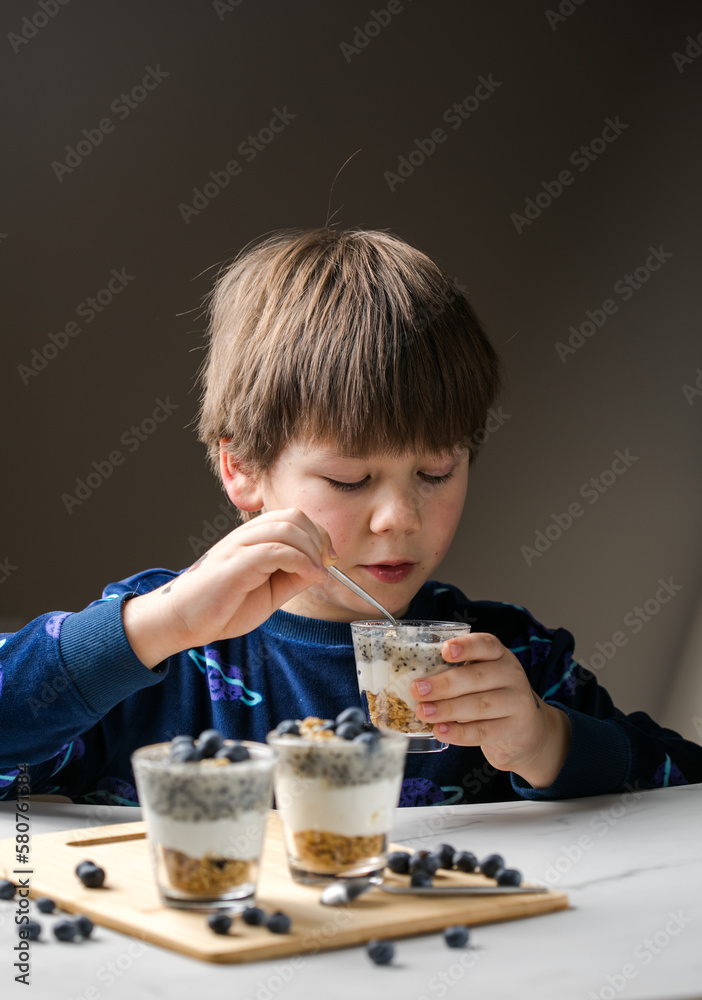 Cute healthy hungry child boy eating breakfast parfait Cute healthy hungry child boy eating breakfast parfait