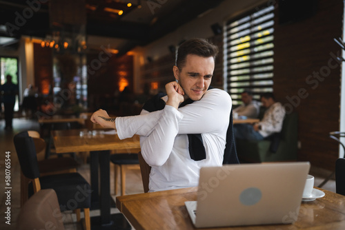 one man sit at the table at restaurant having neck pain or strain