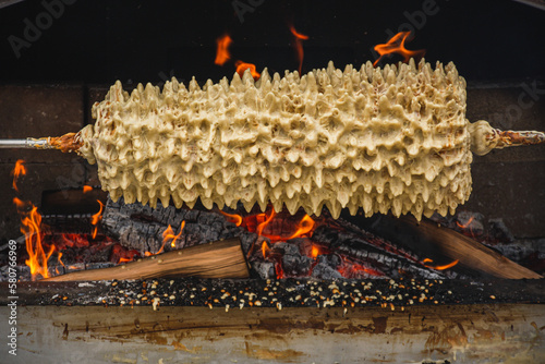 Preparing Lithuanian tree cake, šakotis or baumkuchenas, Polish sękacz, Belarusian bankucha, German baumkuchen made of butter, egg whites and yolks, flour, sugar, and cream, cooked over an open fire photo