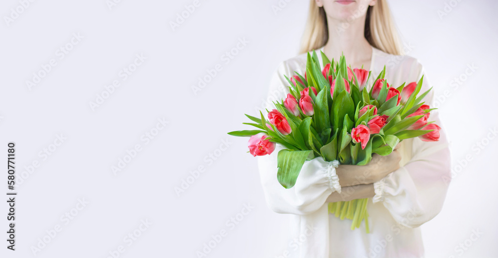 girl florist holds in her hands a beautiful bouquet with tulips on a white background. Spring. Banner. Close up. Space for text on the left