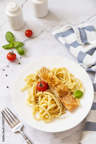 Gluten-free spaghetti pasta with grilled salmon in cream cheese on a marble background.