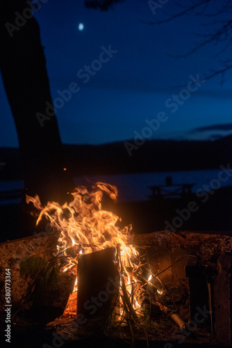 A campfire on Taylor Pond in the Adirondack mountains with a slight illuminatio of the moon