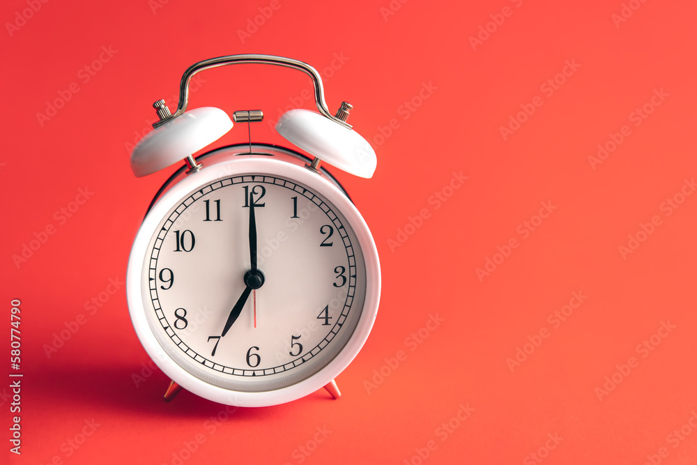 White alarm clock on a blurred red background. White alarm clock on a blurred red background.