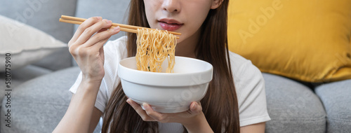 Happy temptation, cute attractive asian young student woman, girl using chopsticks eating instant ramen, noodles soup in bowl in living room at home, cooking meal fast food lifestyle of person.