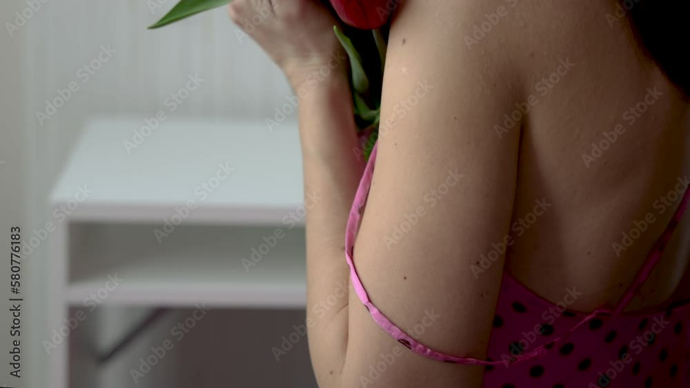 delicate woman with tulips flowers smiling caresses hands neck belly abdomen tummy with one flower tulip.smiling millennial female use smartphone send message hold bouquet inside pants.spring easter