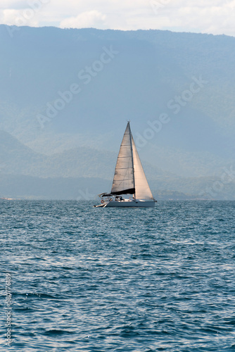 Sailboat sailing in the sea of Paraty, Rio de Janeiro, Brazil. In the background the Bocaina Mountains.