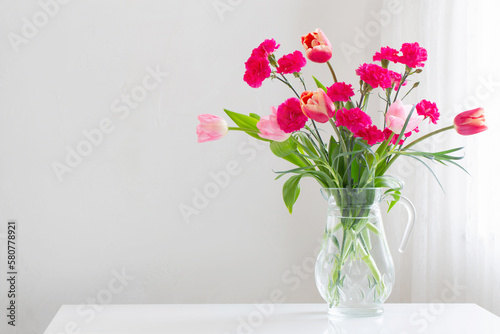 pink spring flowers in glass jug on white background