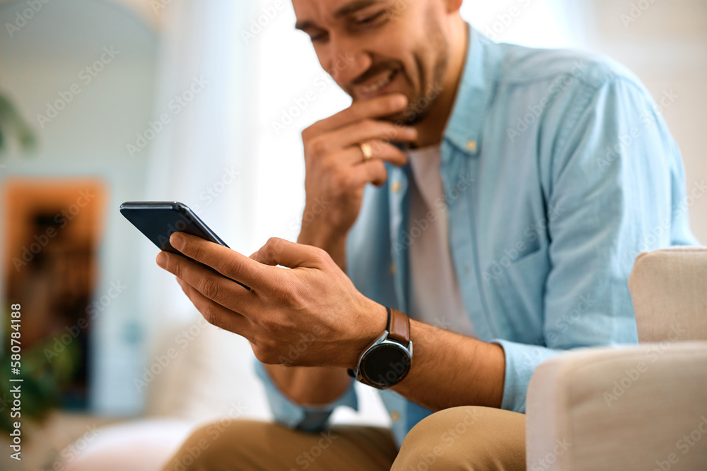 Close up of happy man reads text message on cell phone at home. Close up of happy man reads text message on cell phone at home.