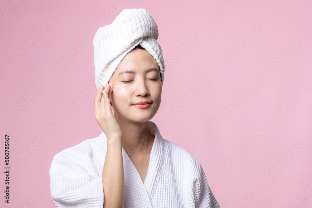 Beautiful young asian woman happy with clean face skin in towel and bathrobe, spa suit on pink background. Skincare, treatment, wellness therapy, facial care, beauty female health, cosmetology concept Beautiful young asian woman happy with clean face skin in towel and bathrobe, spa suit on pink background. Skincare, treatment, wellness therapy, facial care, beauty female health, cosmetology concept