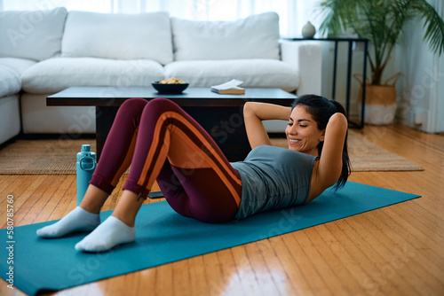 Female athlete exercising sit-ups while working out at home.