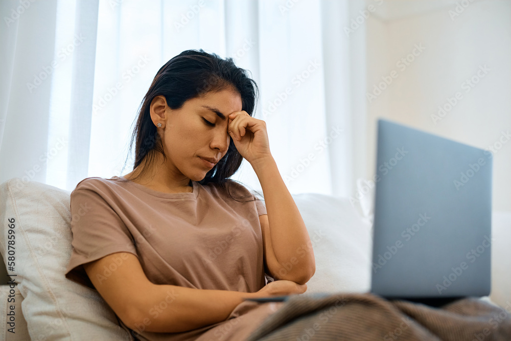 Distraught woman has headache while using laptop at home. Distraught woman has headache while using laptop at home.