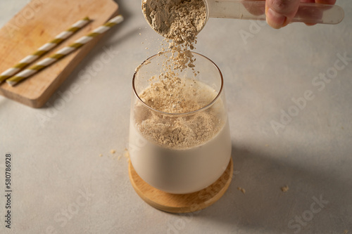 Pouring protein powder from scoop, in glass with milkshake.  photo