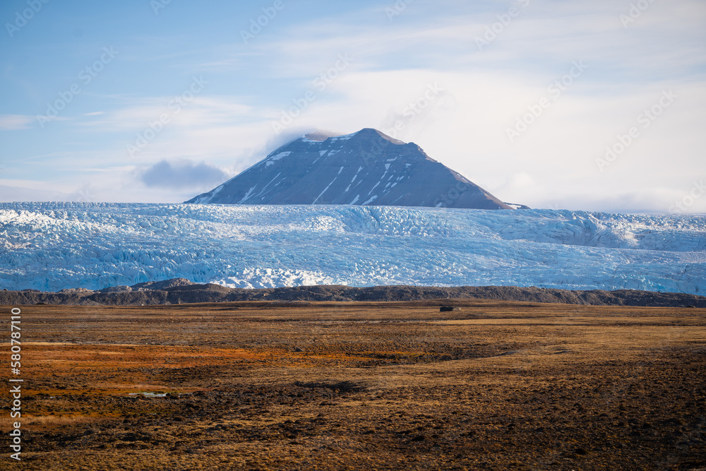 Obraz premium Majestic landscape with a mountain peaking up behind a glacier.