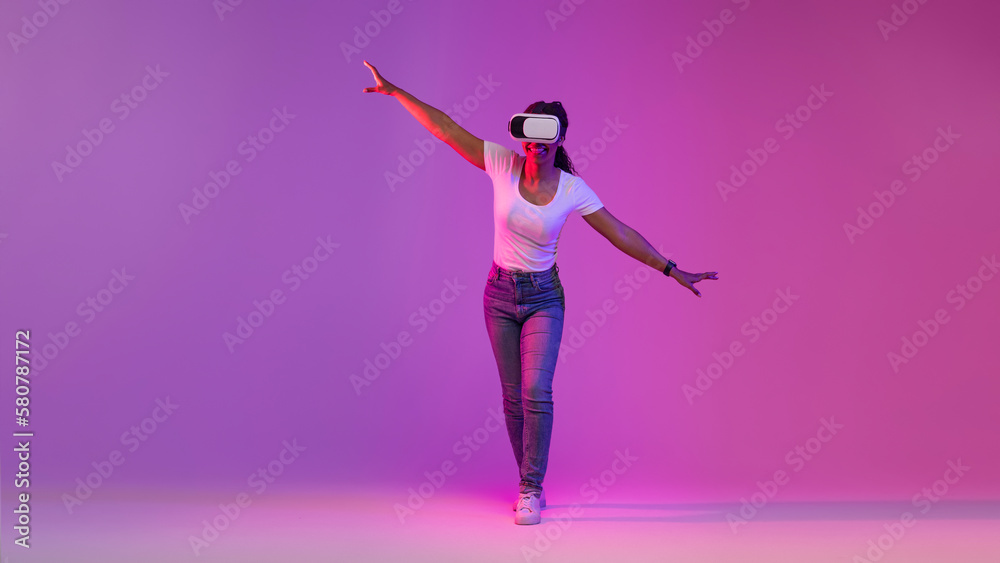 Black Woman In VR Headset Exploring Cyberspace Activities, Walking In Neon Light Black Woman In VR Headset Exploring Cyberspace Activities, Walking In Neon Light