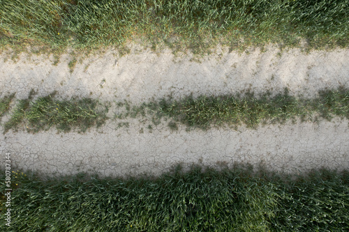 Drone scenery of secondary dry  rural road crossing a farmland meadow
