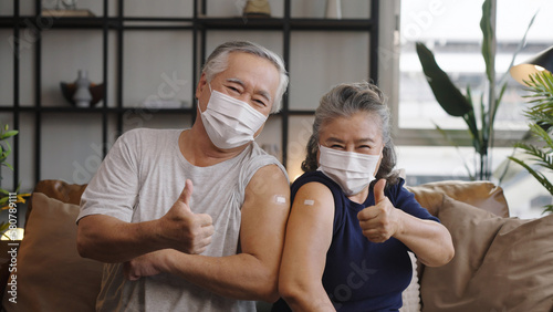 Foto Asian mature couple show shoulder with band aid after injection and giving a thumbs up after being vaccinated