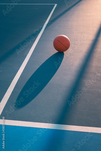 Detail of a ball on a basketball court at sunset. Set of lights, shadows and lines © Cristian Blázquez