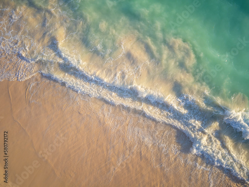 Sea wave and sandy shore. A white foamy wave runs over a white sandy beach. The beauty of nature, climate, weather, ecology. Minimalism. Abstraction. photo