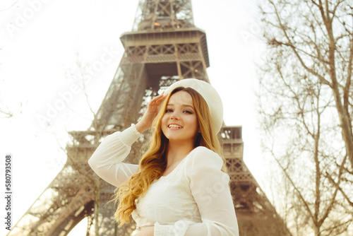 Canvas Print An incredibly beautiful girl in a long white dress and a beret against the background of the Eiffel Tower