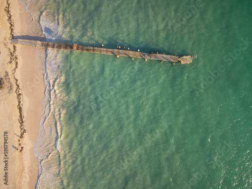 Wooden pier on the sea. White sandy beach. There is no one in the photo. Romance, solitude, sports, fishing, ecology, climate, environmental protection.