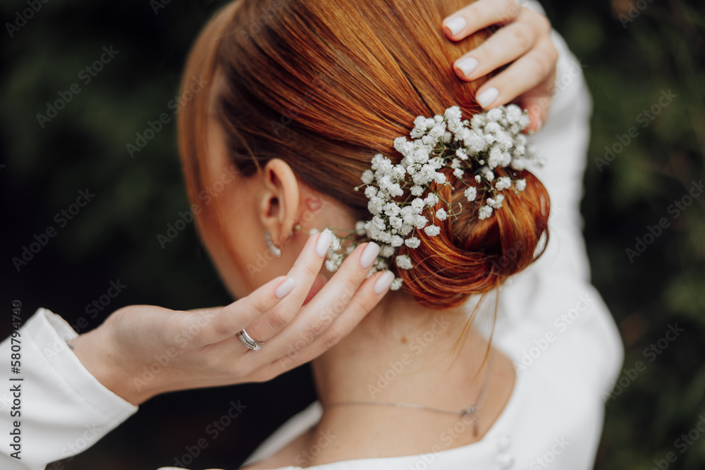 A beautiful young red-haired bride is preparing for her wedding. Flowers in hair. Hairstyle with gypsophila A beautiful young red-haired bride is preparing for her wedding. Flowers in hair. Hairstyle with gypsophila