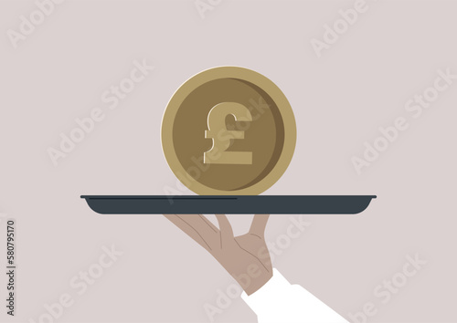 A hand holding a big GBP coin on a tray