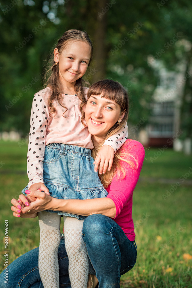 A young beautiful dark-haired mother is resting in a summer park with her young daughter. A young beautiful dark-haired mother is resting in a summer park with her young daughter.