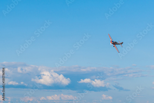 Small retro airplane, light aircraft flying in blue cloudy sky and doing stunts at Air Show. Performance, extreme, aerobatic and sport concept photo