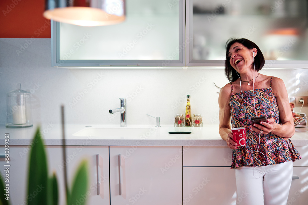 Woman laughing while using the mobile phone and drinking coffee