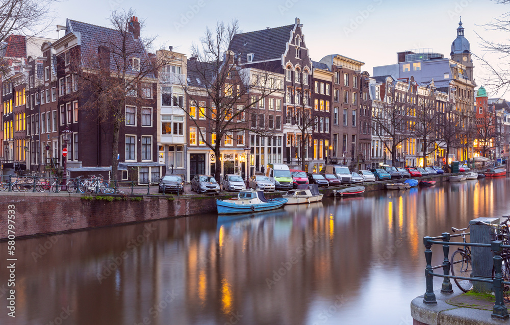 Beautiful old houses on the city embankment of Amsterdam at sunset.