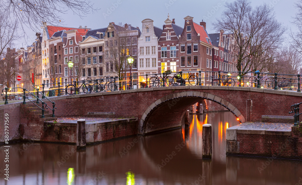 Beautiful old houses on the city embankment of Amsterdam at sunset.