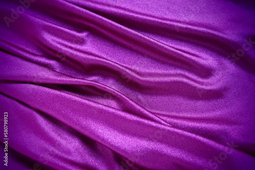 Velour fabric, similar to silk. Textiles in a folds and beautiful waves. Purple, pink, magenta shades on the drapery. Sewing material for evening dresses, furniture upholstery, curtains and interior.