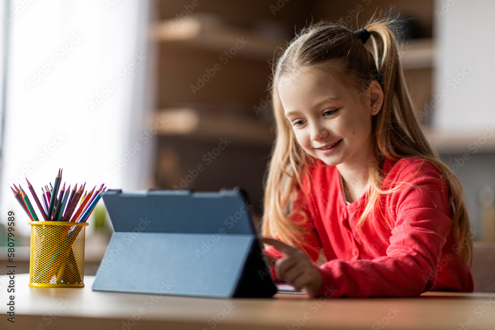 Cute Preteen Girl Using Digital Tablet While Sitting At Desk At Home Cute Preteen Girl Using Digital Tablet While Sitting At Desk At Home