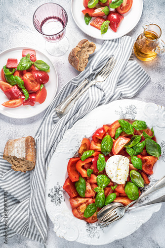 Tomatoes  bell pepper  mozzarella and basil Salad. Bread  olive oil  cutlery. Healthy mediterranean food.  Caprese. Appetizing laid table. Top view.