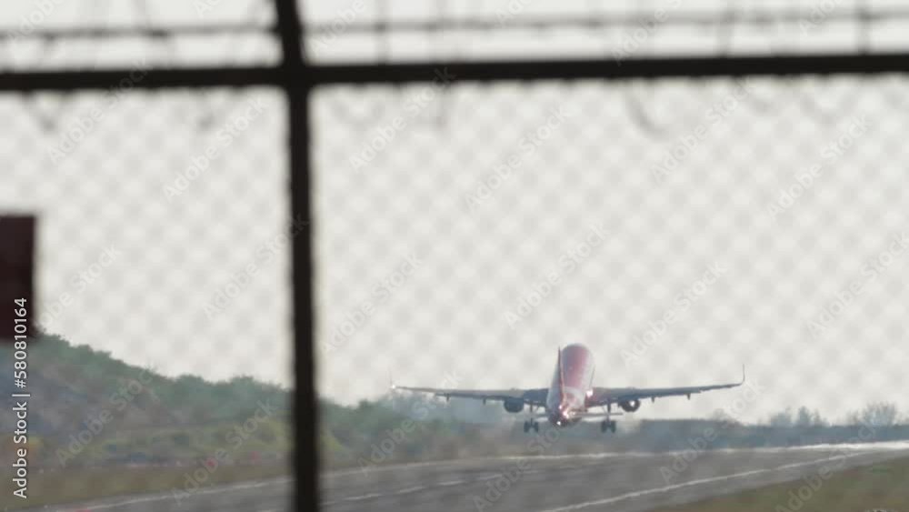 Commercial jet aircraft speed up and takeoff at Phuket airport, rear view. Airplane leaving, long shot. Tourism travel concept