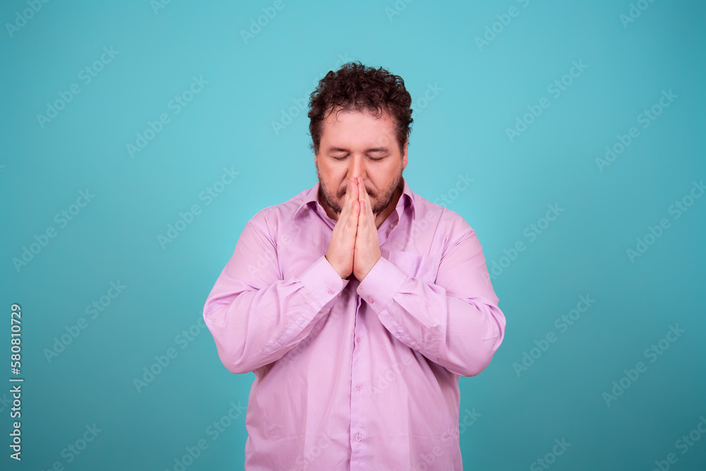 The believing man folded his palms and prays. Culture and religions. Blue background. The believing man folded his palms and prays. Culture and religions. Blue background.