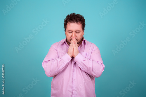 The believing man folded his palms and prays. Culture and religions. Blue background.