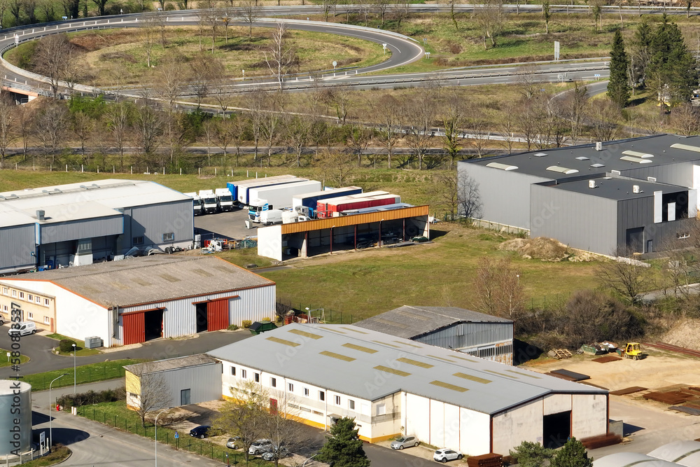 Fototapeta premium Aerial view of goods warehouses and logistics center in industrial city zone from above
