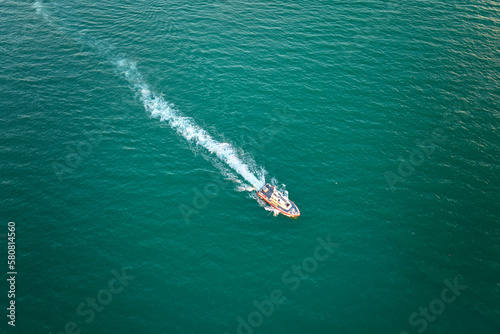 Aerial view of white yacht swimming on sea waves with ripple surface. Motor boat in motion on ocean © bilanol
