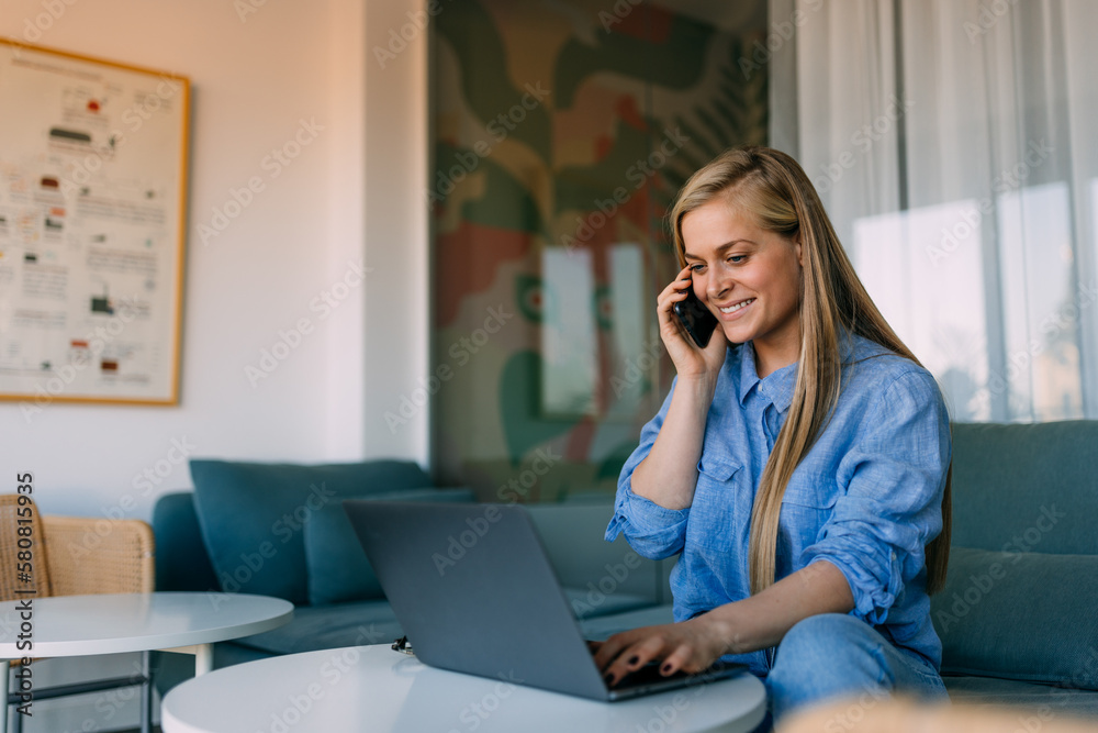 Smiling girl using a laptop while talking to someone over the phone. Smiling girl using a laptop while talking to someone over the phone.