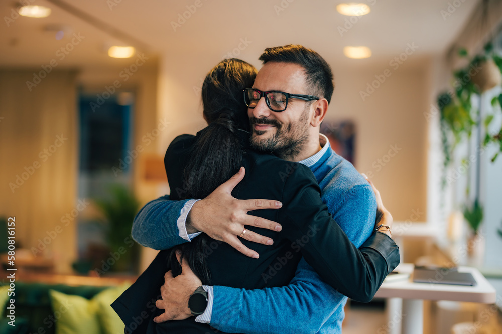 Smiling business colleagues hugging each other at the office. Smiling business colleagues hugging each other at the office.