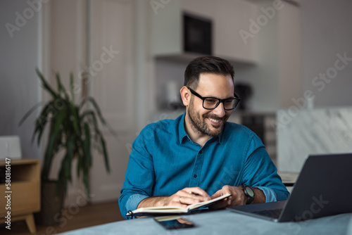 Smiling man working over the laptop, having an online meeting, sitting at the home office.