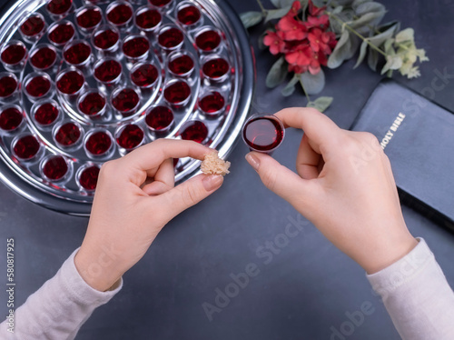 Closeup of young woman taking communion from small cups on black background