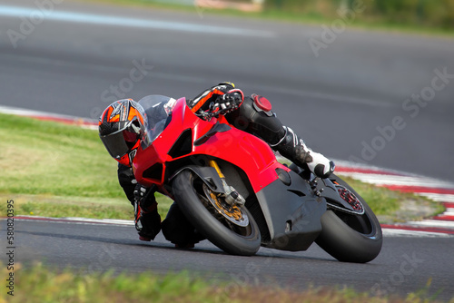 a motorcycle rider on a red sport bike riding through a corner at high speed  leaning the bike  dragging a knee and an elbow