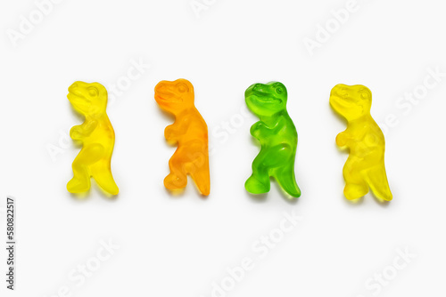 Fototapeta Naklejka Na Ścianę i Meble -  Four multi-colored dinosaur shaped gummy candies on a white background. Colorful sweet confectionery on an isolated white background. Multicolored jelly candies lined up in a row