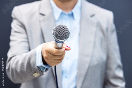 Female journalist holding microphone making media interview