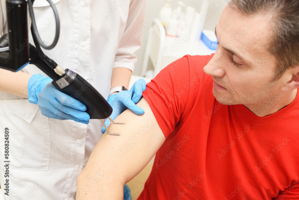cosmetologist uses a CO2 fractional ablative laser to rejuvenate the skin and remove scars to a male patient in a modern cosmetic beauty clinic. cosmetologist uses a CO2 fractional ablative laser to rejuvenate the skin and remove scars to a male patient in a modern cosmetic beauty clinic.