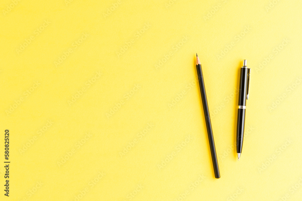 Office desktop with black pen and pencil on yellow background. Top view Office desktop with black pen and pencil on yellow background. Top view