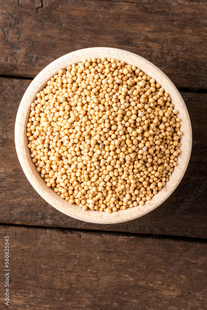White mustard seeds in bowl on wooden table. Close up. Top view White mustard seeds in bowl on wooden table. Close up. Top view